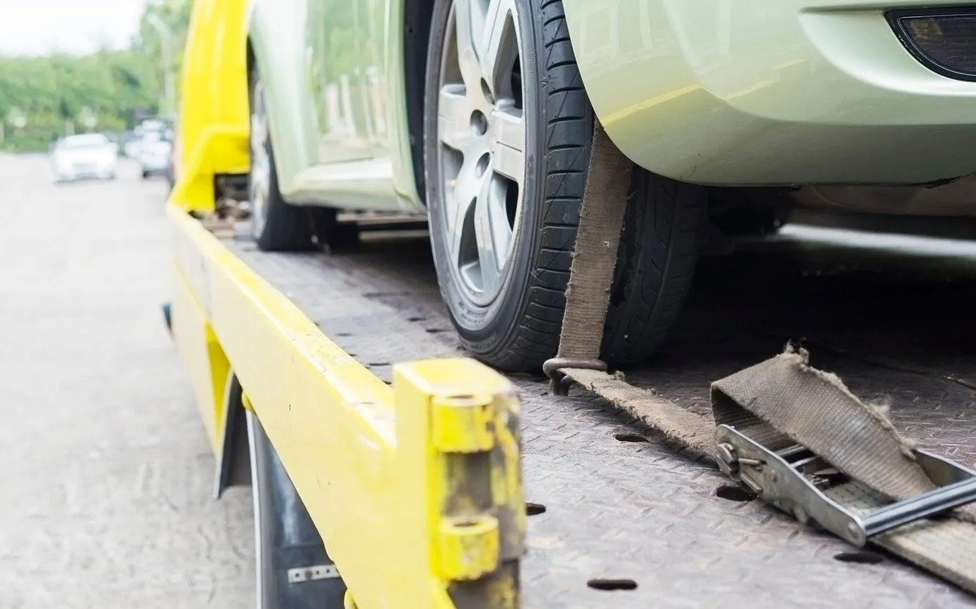 A car being winched onto the back of a yellow tow truck